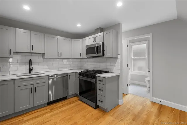 a kitchen with stainless steel appliances granite countertop a stove top oven a sink and dishwasher a refrigerator with wooden floor