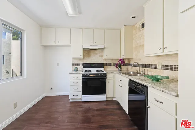 a view of a room with wooden floor chandeliers and kitchen view