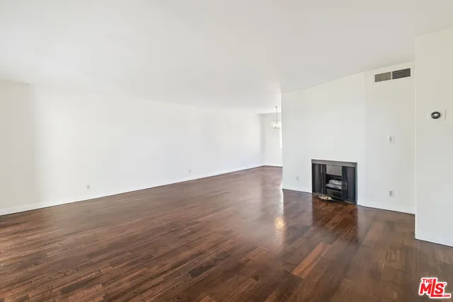 an empty room with wooden floor and fireplace