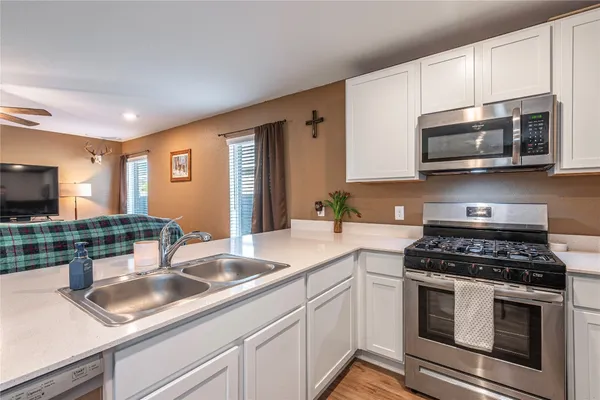 a kitchen with stainless steel appliances granite countertop a sink a stove a microwave and wooden cabinets