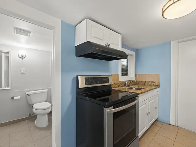 a kitchen with stainless steel appliances a stove and white cabinets