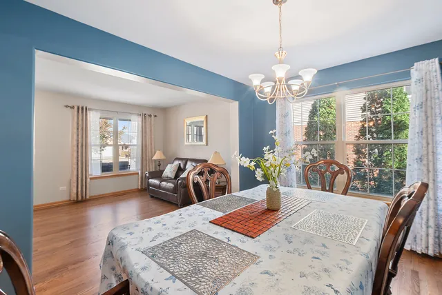 a kitchen with stainless steel appliances granite countertop a stove top oven a refrigerator a dining table and chairs with wooden floor