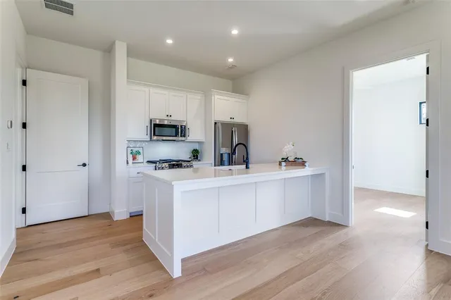 a kitchen with white cabinets and stainless steel appliances