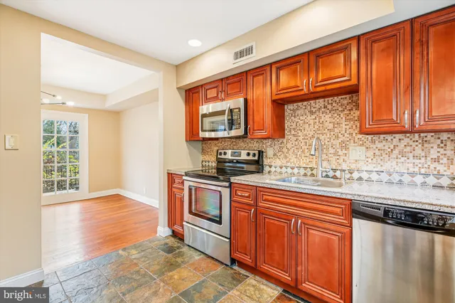 a kitchen with stainless steel appliances granite countertop a stove sink and cabinets
