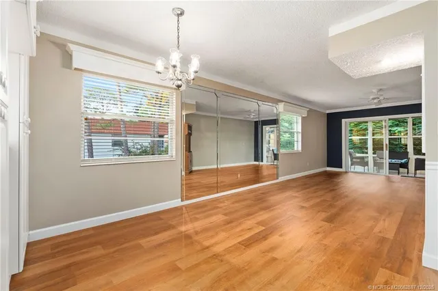 an empty room with a chandelier fan and windows