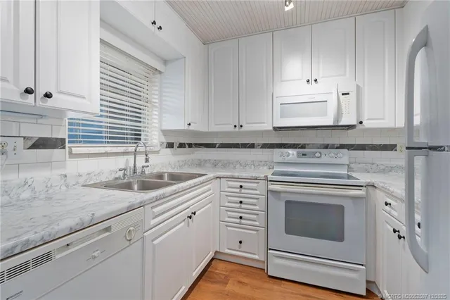 an empty room with wooden floor cabinet and windows