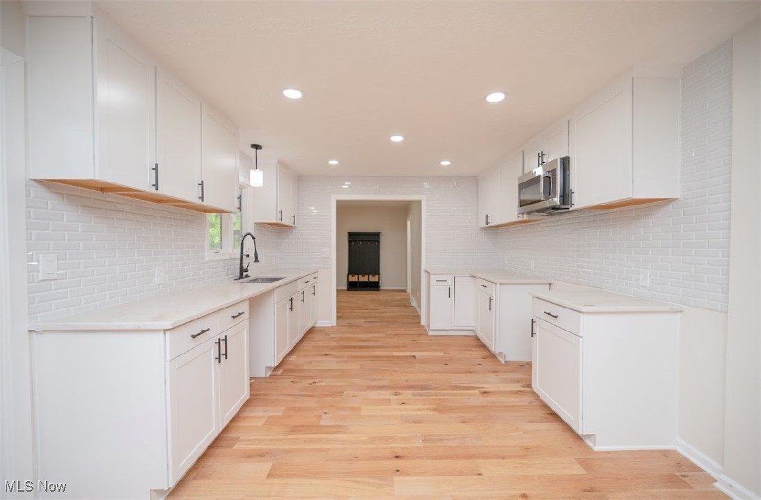 6006 Tippecanoe Road Canfield, OH 44406 - Photo 11 of 35 Kitchen with stainless steel microwave, a sink, light wood-style flooring, decorative backsplash, and recessed lighting