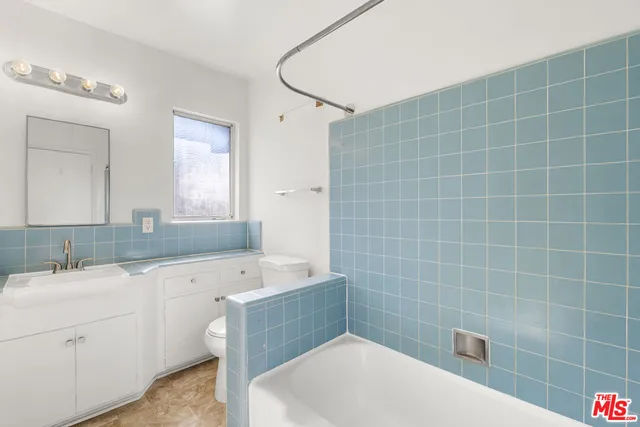 a bathroom with a sink a toilet a mirror and bathtub