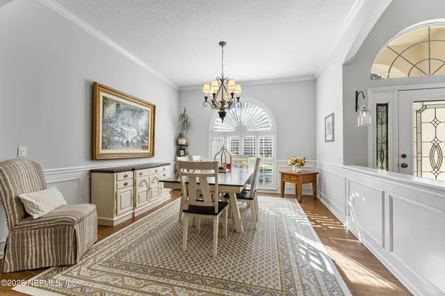 a dining room with furniture a chandelier and wooden floor