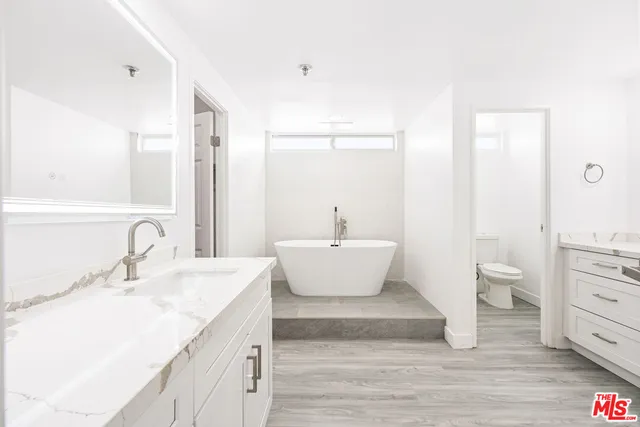 a bathroom with a white tub a sink and a large mirror