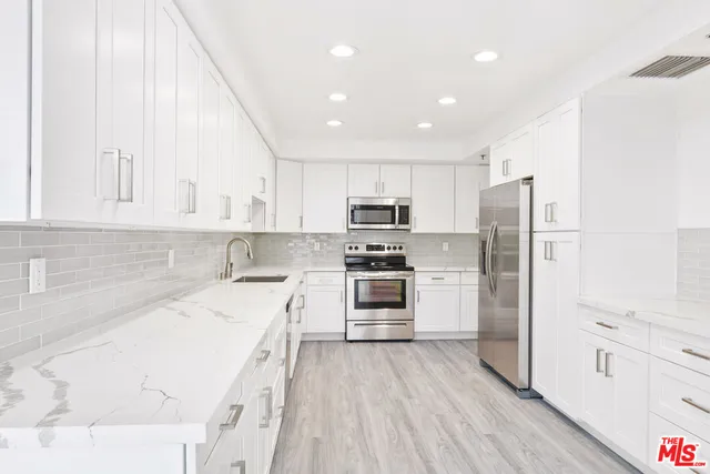 a kitchen with white cabinets and stainless steel appliances
