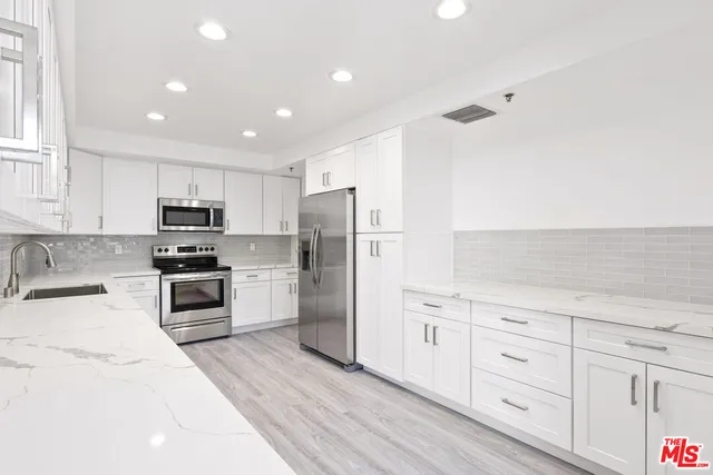 a kitchen with granite countertop white cabinets and stainless steel appliances