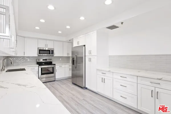 a kitchen with granite countertop white cabinets and stainless steel appliances