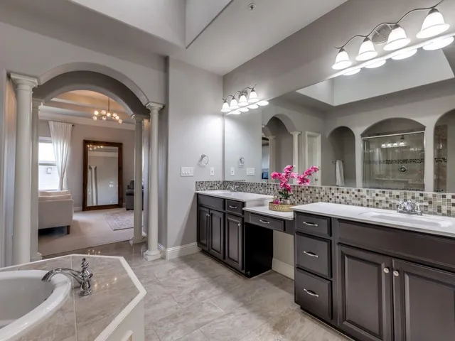 a spacious bathroom with a granite countertop sink a large mirror and a shower