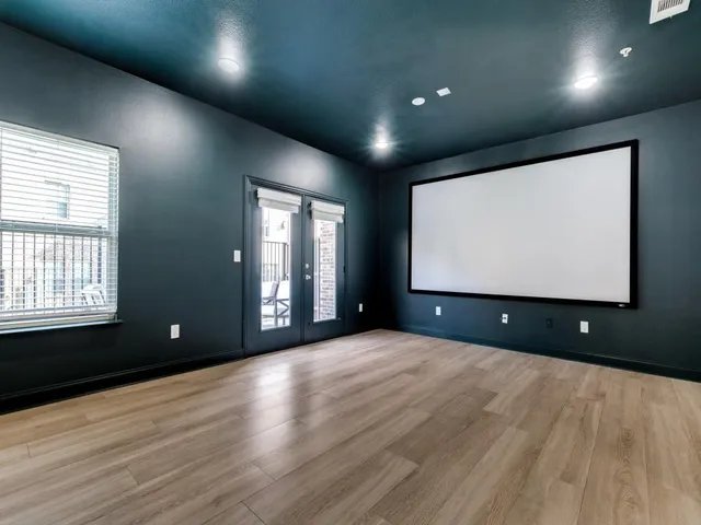 a view of an empty room with wooden floor and windows