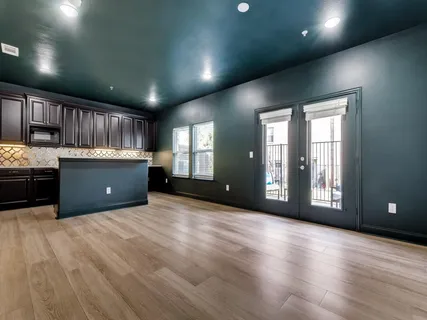 a view of an empty room with a kitchen and window