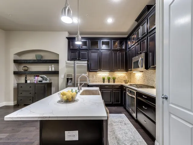 a kitchen with kitchen island granite countertop a sink stainless steel appliances and cabinets