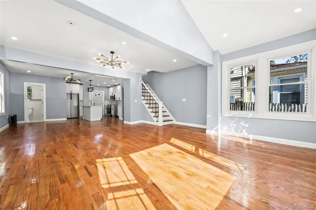 a view of an empty room with kitchen and windows