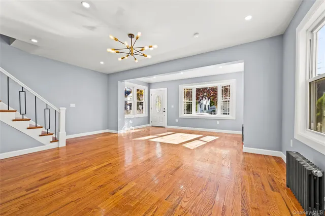 a view of an empty room with window and wooden floor