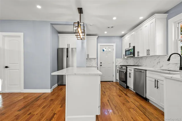 a kitchen with a sink a center island stainless steel appliances and cabinets
