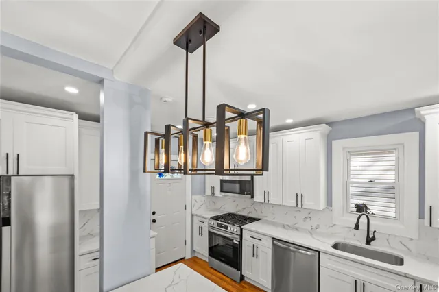 a kitchen with stainless steel appliances granite countertop a sink a stove and a refrigerator