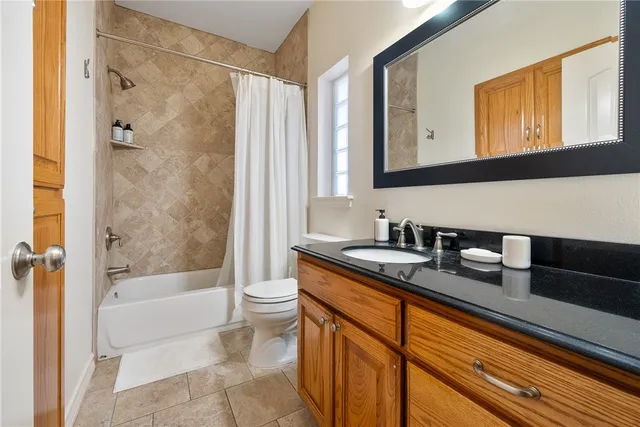 a bathroom with a granite countertop sink a mirror a bathtub and shower