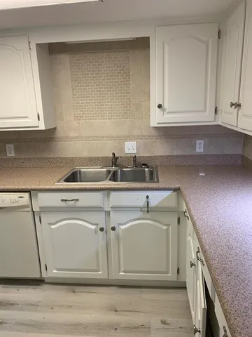 a kitchen with stainless steel appliances white cabinets and wooden floors