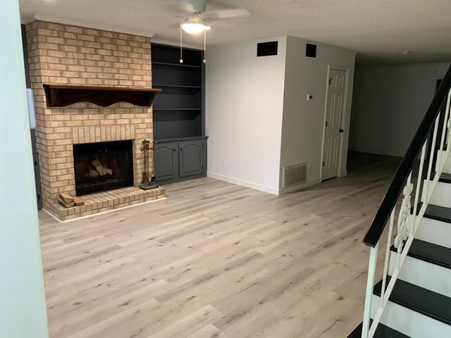 a view of an empty room with wooden floor and a fireplace