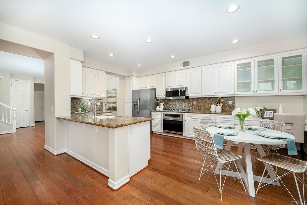 5406 Foxtail Loop Carlsbad, CA 92010 - Photo 14 of 50 a kitchen with stainless steel appliances granite countertop a stove top oven a sink refrigerator and white cabinets with wooden floor