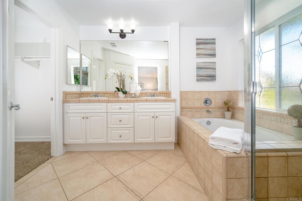 5406 Foxtail Loop Carlsbad, CA 92010 - Photo 24 of 50 a spacious bathroom with a double vanity sink a mirror a bathtub and next to a window