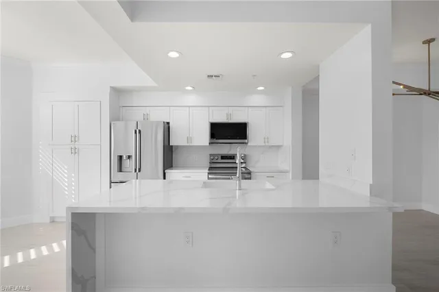 a view of kitchen with stainless steel appliances kitchen island sink and refrigerator