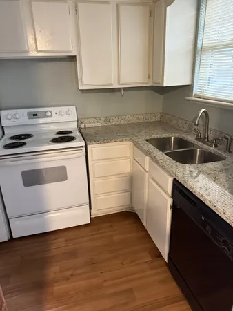 a kitchen with granite countertop white cabinets and white appliances