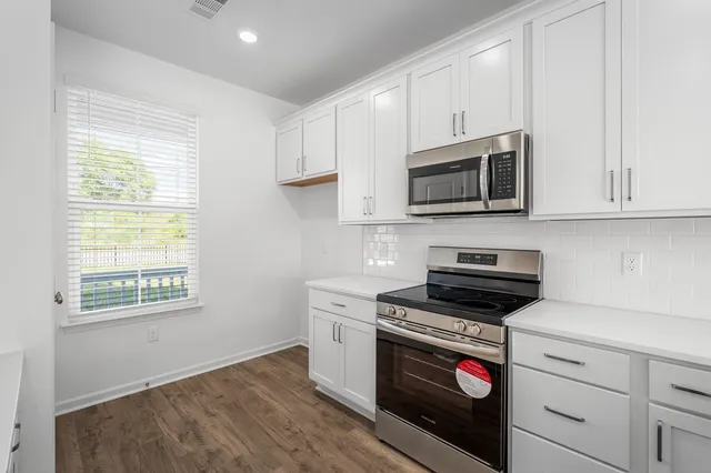 a kitchen with granite countertop white cabinets appliances and a window