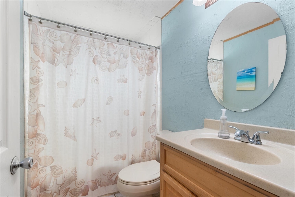 63 Baldwin Road Billerica, MA 01821 - Photo 16 of 38 a bathroom with a granite countertop sink a toilet and a mirror