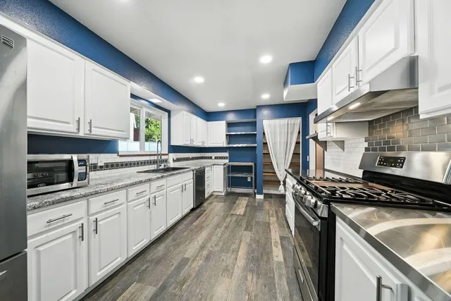 a kitchen with stainless steel appliances granite countertop a stove a sink and a microwave