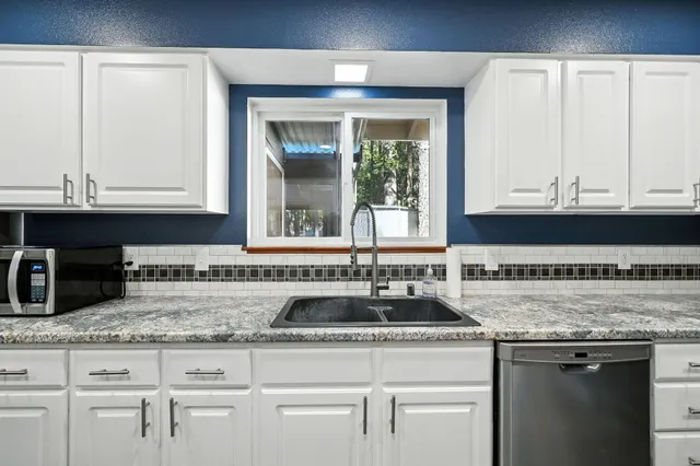 a kitchen with granite countertop a sink a stove and cabinets