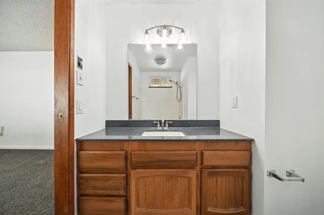 a bathroom with a granite countertop sink and a mirror