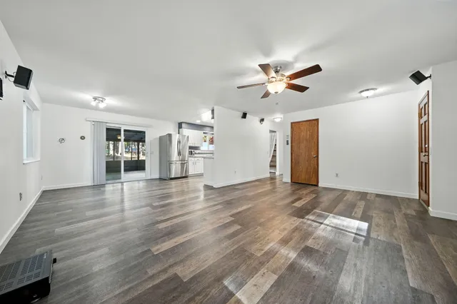 a view of an empty room with a window and a kitchen