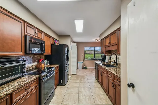 a kitchen with stainless steel appliances granite countertop a stove top oven a sink dishwasher and a refrigerator