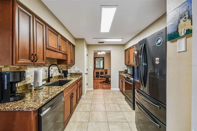 a kitchen with granite countertop a refrigerator stove and sink