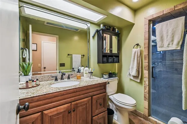 a bathroom with a granite countertop toilet sink and mirror