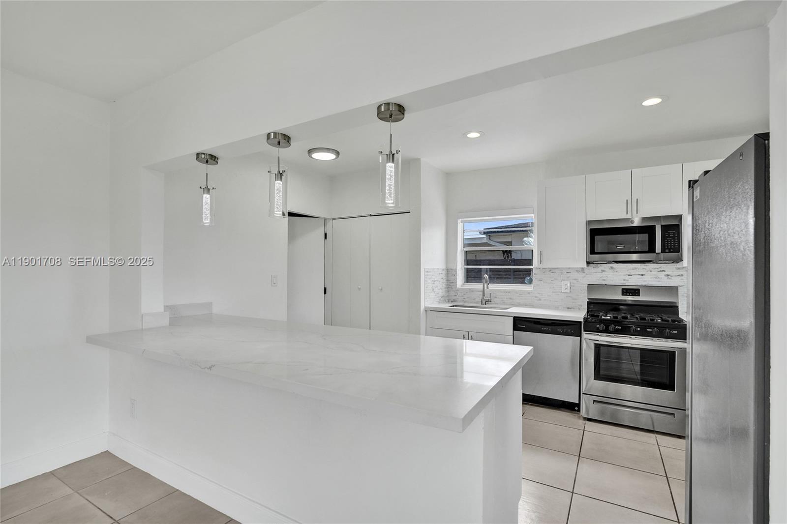 5750 Northwest 111th Street Hialeah, FL 33012 - Photo 3 of 34 a open kitchen with stainless steel appliances kitchen island granite countertop a refrigerator and a stove top oven