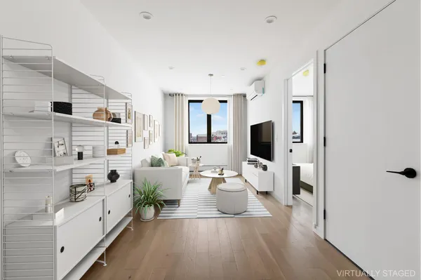 a large white room with stainless steel appliances kitchen island a large window and a couch