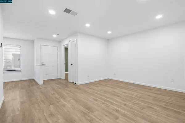 an empty room with wooden floor and windows