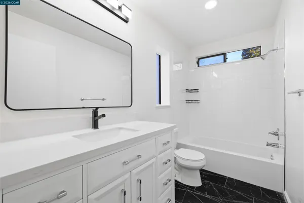 a bathroom with a granite countertop sink a toilet and a bathtub