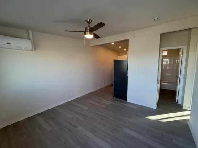 an empty room with wooden floor and ceiling fan