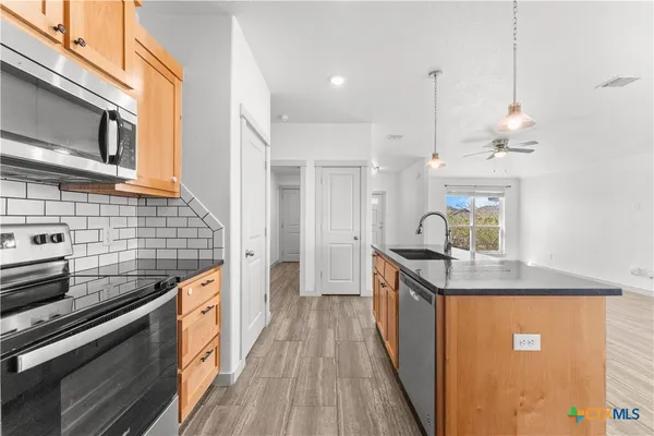 a kitchen with granite countertop a sink a counter space stainless steel appliances and cabinets