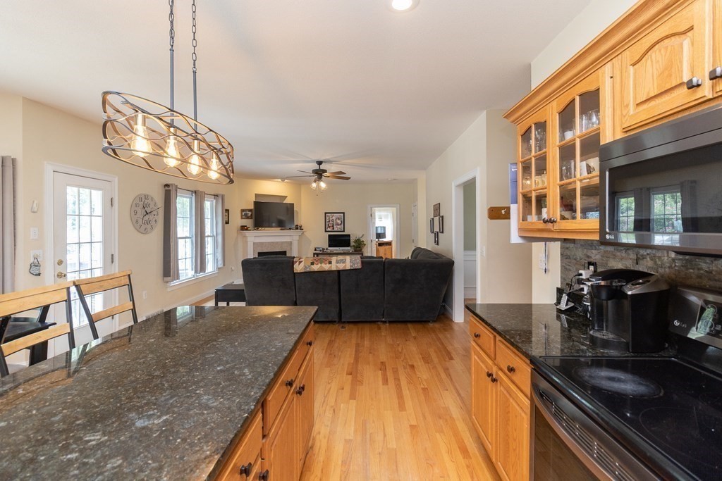 46 Radisson Lane Westfield, MA 01085 - Photo 6 of 40 a large kitchen with kitchen island a stove a sink dishwasher a dining table and chairs with wooden floor
