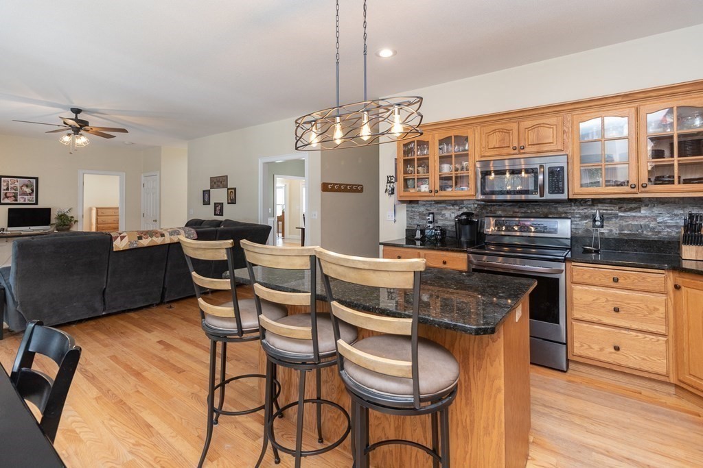 46 Radisson Lane Westfield, MA 01085 - Photo 7 of 40 a kitchen with stainless steel appliances granite countertop a stove top oven a dining table and chairs with wooden floor