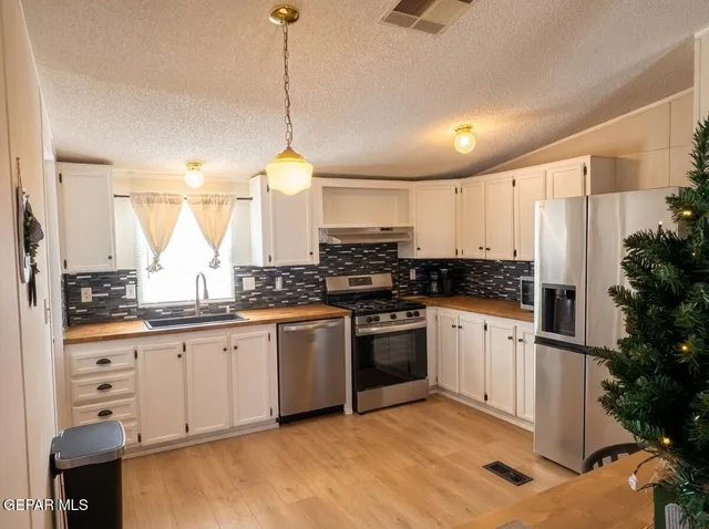 a kitchen with stainless steel appliances granite countertop a stove a sink and white cabinets